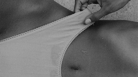 Woman in soft white bralette, hand tucked under elastic